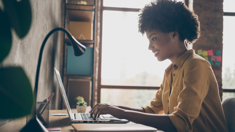 Woman sitting at desk typing on laptop