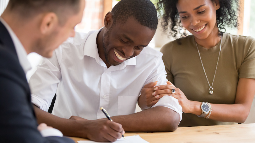 young couple signing document with loan officer