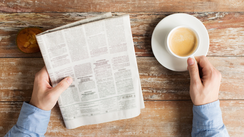 close up of male hands with newspaper and coffee