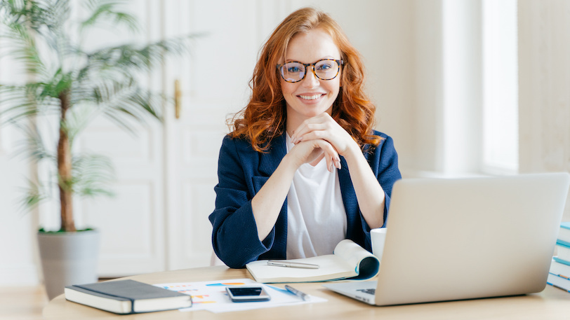 young business woman sitting at desk and smiling